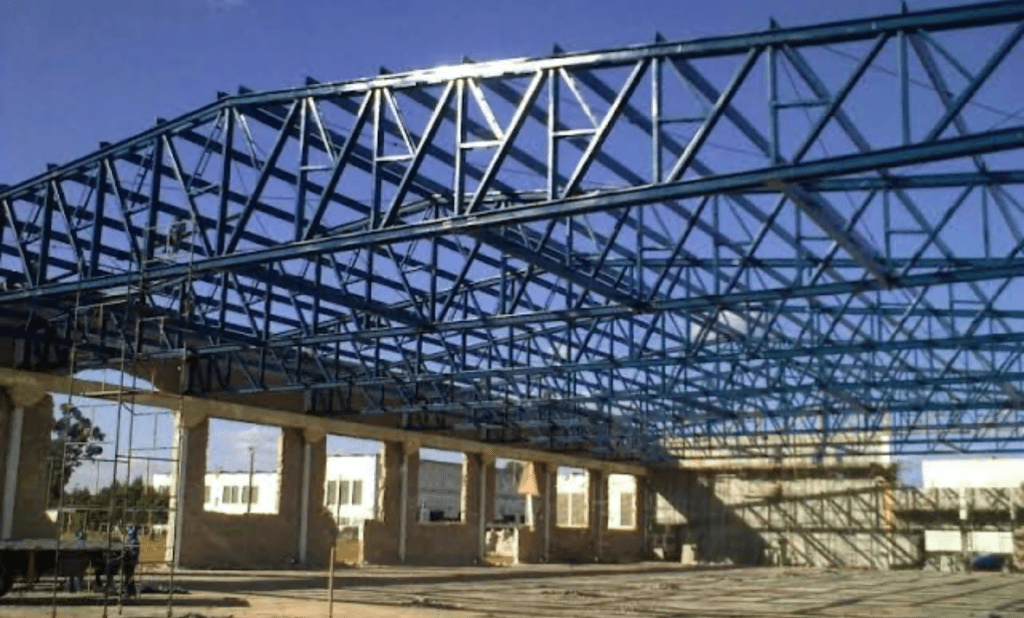 A imagem demonstra os resultados concretos da montagem de uma estrutura metálica do telhado de uma edificação.